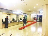 コンビニエンスストアを通り過ぎたすぐの角を右に、次の角を左に曲がります。少し進むとエレベーターホールへの案内板が見えます。【画像】